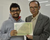A foto apresenta o discente Vitor Alcântara Fernandes da Silva sorrindo, junto ao professor Julio Zukerman Schpector, ambos segurando o certificado do prêmio Mário Tolentino.